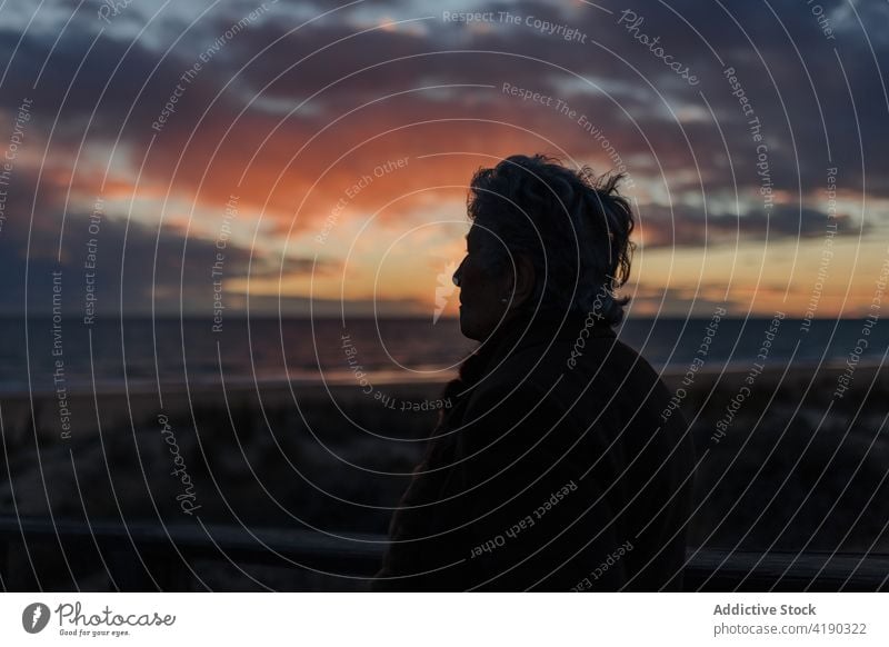 Ältere Dame bewundert den Sonnenuntergang über dem Meer von der Strandpromenade aus Frau bewundern Meereslandschaft Reisender genießen Natur Urlaub reisen MEER