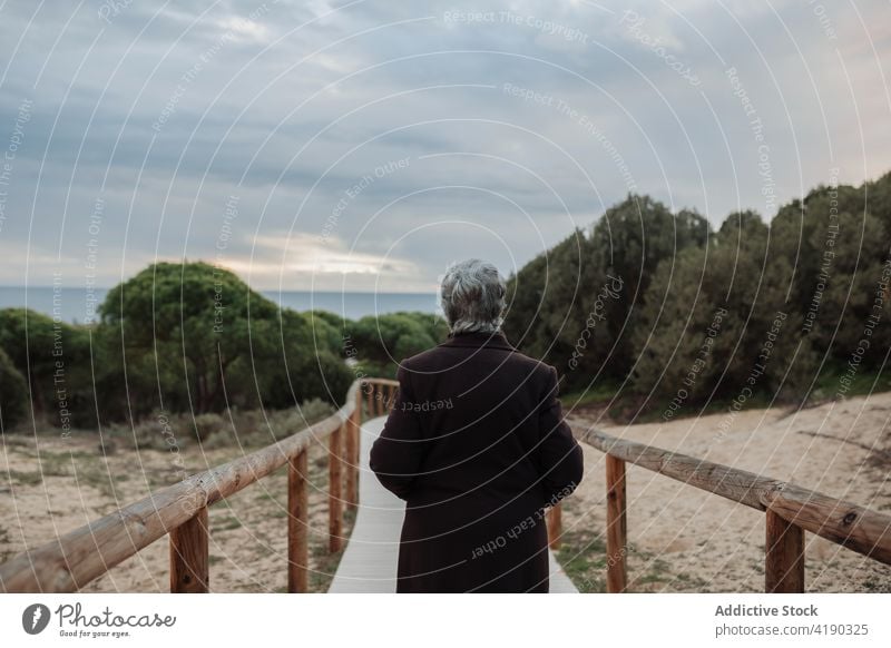 Unerkennbare ältere Dame bewundert den Sonnenuntergang über dem Meer von der Strandpromenade aus Frau bewundern Meereslandschaft Reisender genießen Natur Urlaub