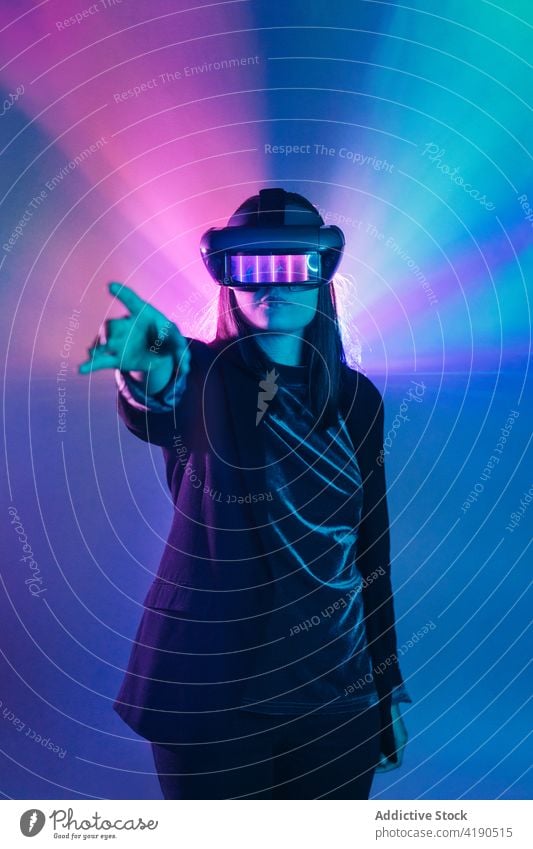 Anonyme Frau mit VR-Brille im Neonlicht Schutzbrille Headset neonfarbig Licht ausdehnen Virtuelle Realität Technik & Technologie Cyberspace leuchten simulieren