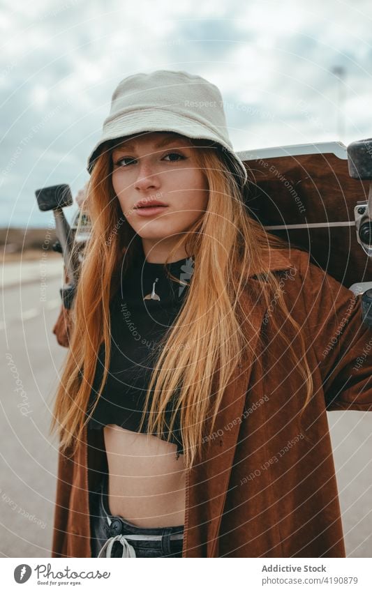 Seriöse junge Frau mit Skateboard in der Hand auf der Straße stehend Landschaft Skater ernst selbstbewusst Aktivität trendy Hobby Sport Natur Cruiser Stil