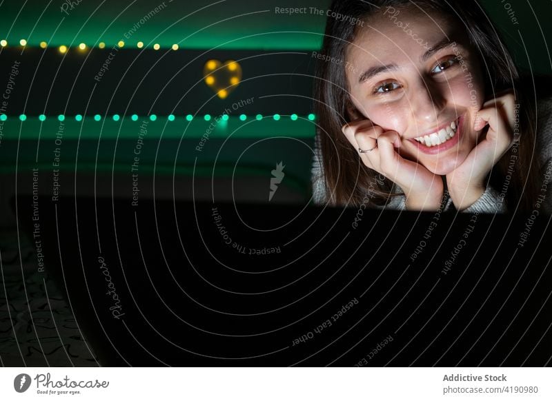 Junges Mädchen surft auf Laptop im Zimmer leuchten heimwärts Browsen Lächeln Teenager Gerät Surfen Raum online heiter Apparatur Internet Schlafzimmer Pullover