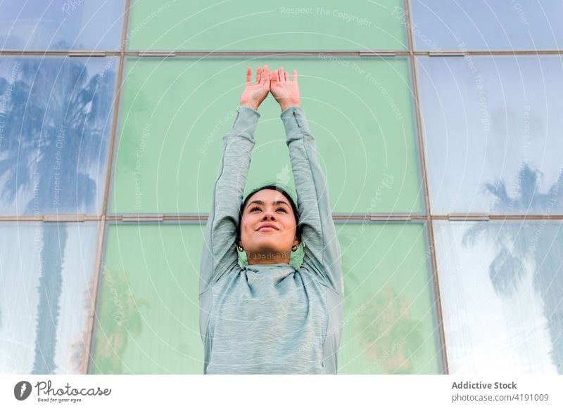 Junge Frau in sportlichem Outfit steht in der Nähe eines städtischen Gebäudes aktiv Stil urban Sportbekleidung Training Fitness passen selbstbewusst jung