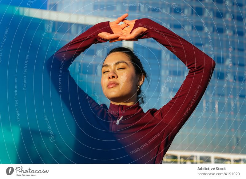 Junge Frau in sportlichem Outfit steht in der Nähe eines städtischen Gebäudes aktiv Stil urban Sportbekleidung Training Fitness passen selbstbewusst jung