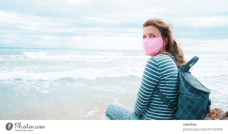 Junge Frau trägt eine rosa Gesichtsmaske sitzt in der Nähe des Meeres Hoffnung Mut stark COVID Coronavirus Strand MEER ocecan frei Freiheit Mundschutz