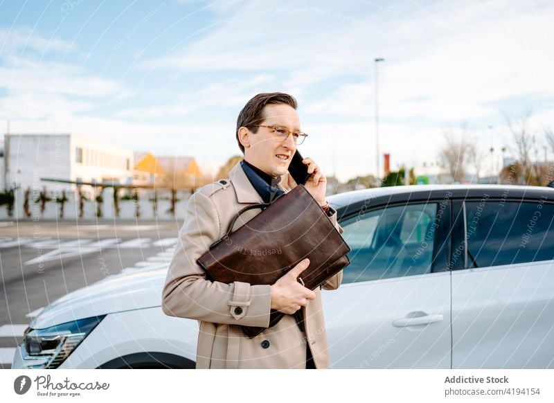 Geschäftsmann, der auf einem Parkplatz mit seinem Smartphone spricht sprechen parken PKW geparkt beschäftigt Unternehmer reden Großstadt männlich Mann