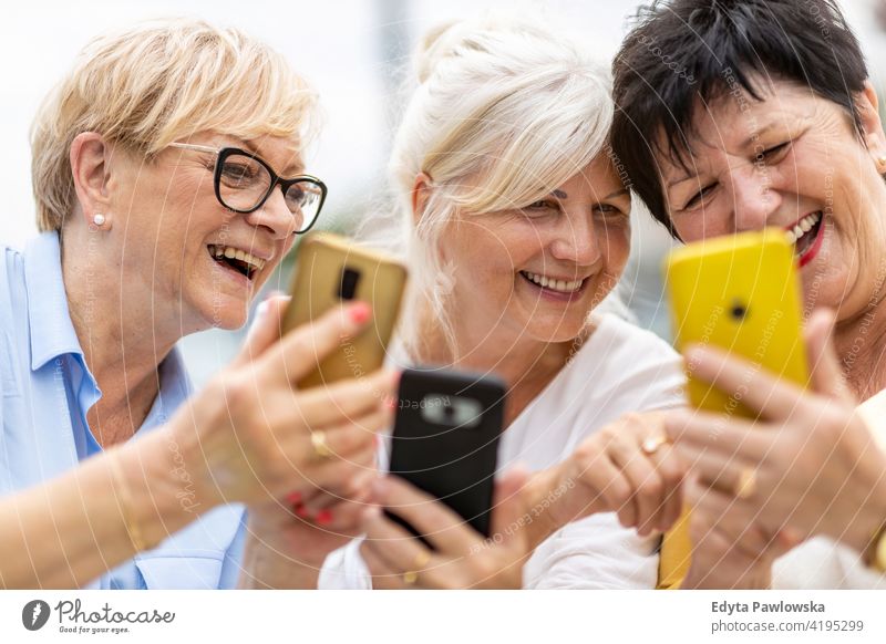 Gruppe älterer Frauen, die gemeinsam ein Smartphone benutzen Senior Menschen in den Ruhestand getreten Großmutter Freizeit Stehen selbstbewusst attraktiv urban