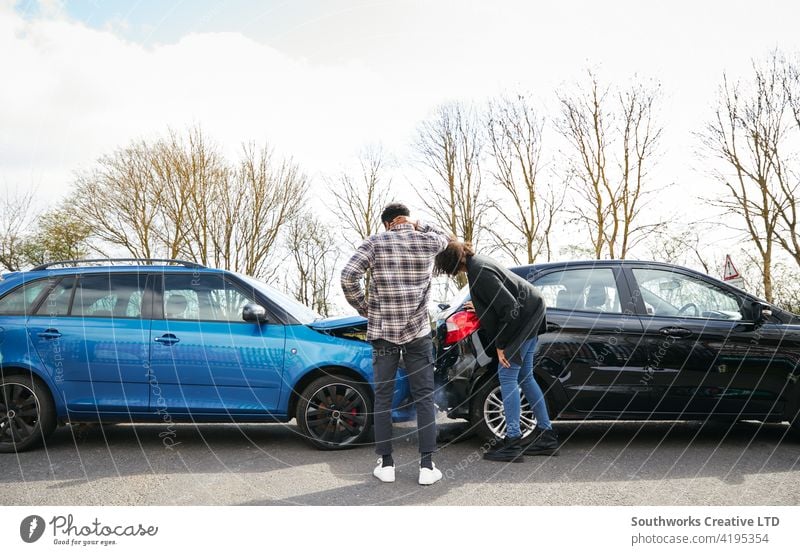 Junge männliche und weibliche Fahrer, die aus dem Auto steigen und den Schaden nach einem Verkehrsunfall inspizieren Frau Mann PKW Unfall Schiffswrack Absturz