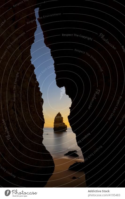 Felsige Klippe in wogenden Meer in der Nähe von Sandstrand bei Sonnenuntergang Strand Höhle Natur Landschaft Meereslandschaft idyllisch malerisch Algarve