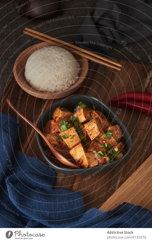 Chinesisches veganes Essen auf Holztisch Lebensmittel Veganer Gerichte Gemüse Tofu Mala-Tofu Mapo-Tofu Blumenkohl Knoblauch rote Paprika Gewürze Abendessen