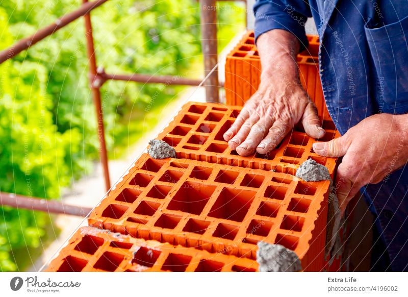 Arbeiter baut Mauer mit roten Blöcken und Mörtel Genauigkeit genau Aktivität Architektur Klotz Baustein Maurer Maurerarbeiten Mauerwerk Bauherr Baustelle