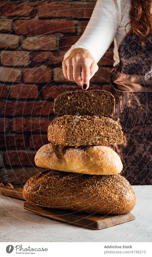 Getreidehandwerker zeigt geschnittenes Mehrkornbrot in der Backstube Bäcker Brot Müsli Nährstoff Protein frisch knackig lecker Frau Bäckerei weich Tisch