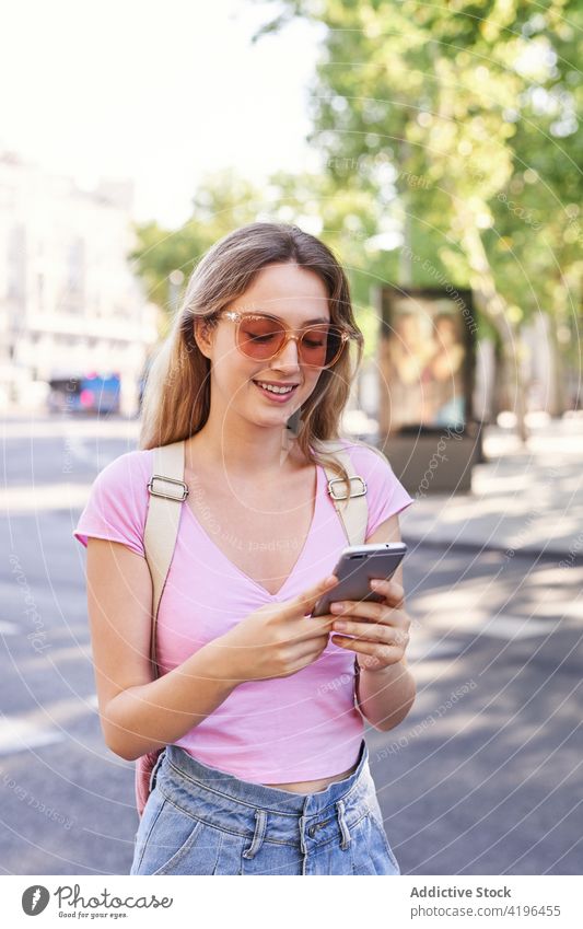 Positiver Teenager-Tourist surft auf seinem Smartphone, während er die Straße auf dem Zebrastreifen überquert Frau Fußgänger prüfen benutzend durchkreuzen Route