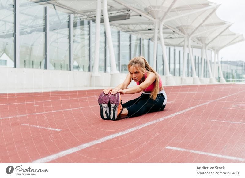 Sportlerin beim Stretching auf dem Trainingsplatz attraktiv stark Kaukasier Vorbereitung Bahn passen Frau Energie Jogger im Freien Ausdauer Gebäude Sportbahn