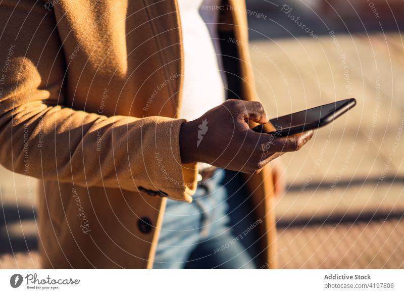 Anonymer stylischer schwarzer Mann benutzt Smartphone auf der Straße benutzend Fokus Stil Browsen Gerät trendy Outfit Apparatur Surfen Telefon Nachricht