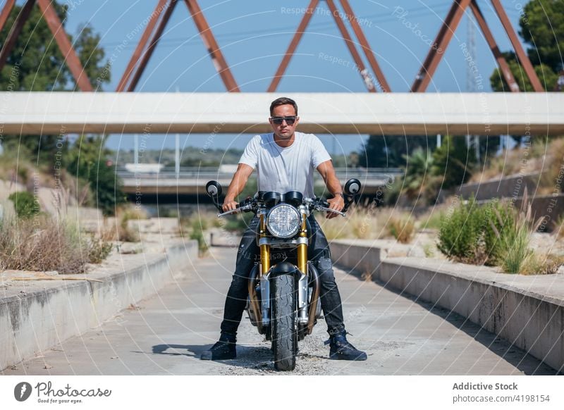 Mann auf modernem Motorrad in der Stadt Biker cool urban Stil Motorradfahrer Fahrzeug selbstbewusst männlich sitzen brutal Graffiti Wand Straßenkunst Verkehr