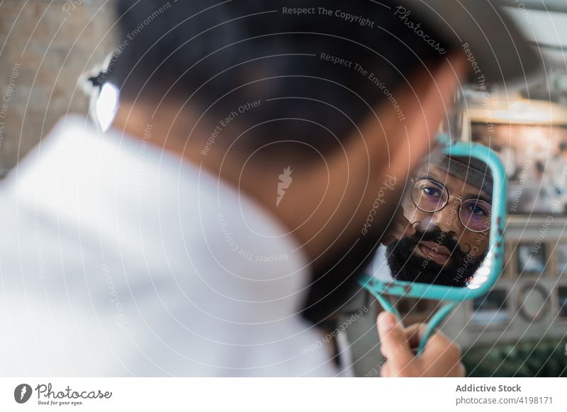 Crop ethnischen Friseur Blick in den Spiegel in Friseursalon Reflexion & Spiegelung Schnurrbart Hipster maskulin brutal Macho Salon Mann Haarpflege Locken