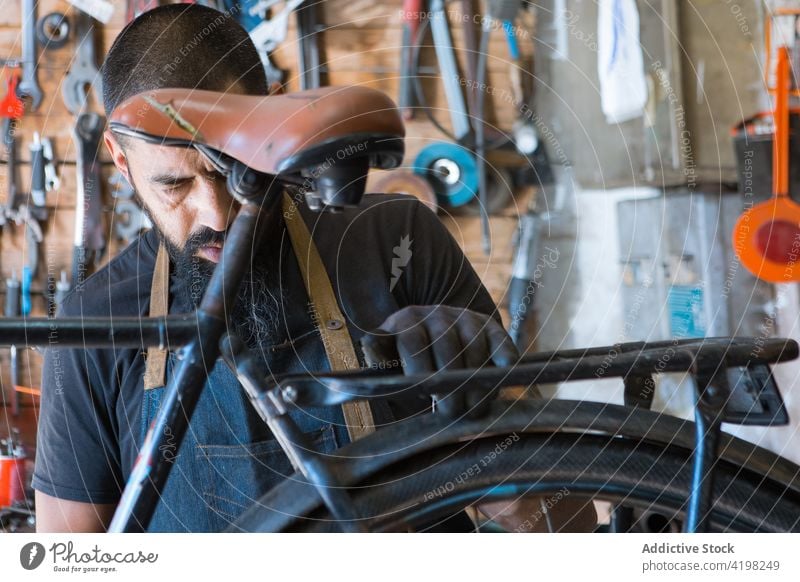 Konzentrierter Mann repariert Fahrrad in Garage Reparatur Fahrzeug Meister vorbereiten Fähigkeit Arbeitsplatz professionell männlich Rad Rand Dienst Reifen