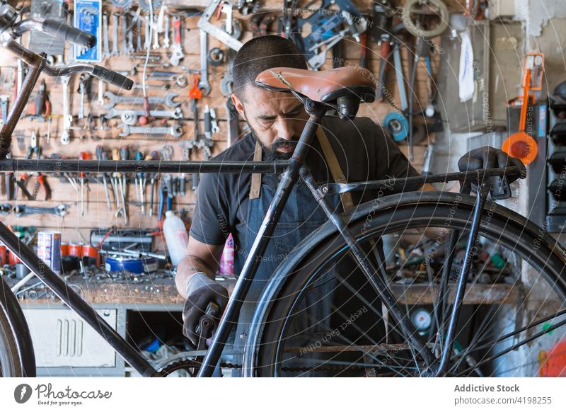 Konzentrierter Mann repariert Fahrrad in Garage Reparatur Fahrzeug Meister vorbereiten Fähigkeit Arbeitsplatz professionell männlich Rad Rand Dienst Reifen