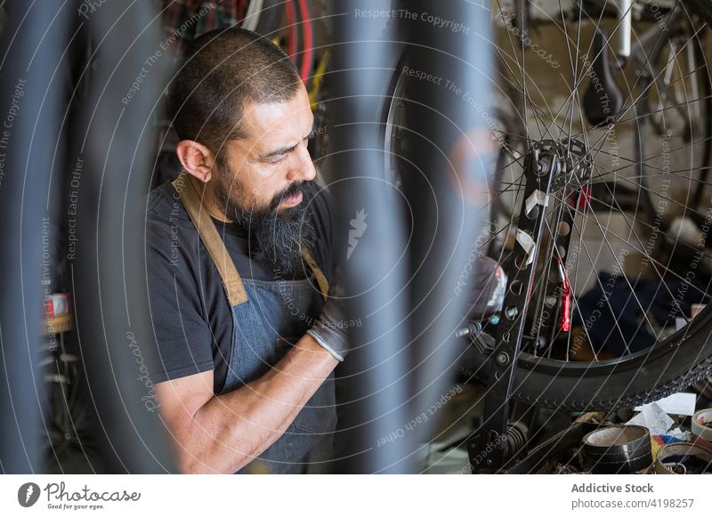 Bärtiger Mechaniker bei der Reparatur eines Fahrrads Mann Rad Garage Reifen Werkstatt Dienst Meister Fähigkeit männlich Fahrzeug vorbereiten professionell