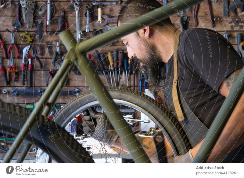 Bärtiger Mechaniker bei der Reparatur eines Fahrrads Mann Rad Garage Reifen Werkstatt Dienst Meister Fähigkeit männlich Fahrzeug vorbereiten professionell