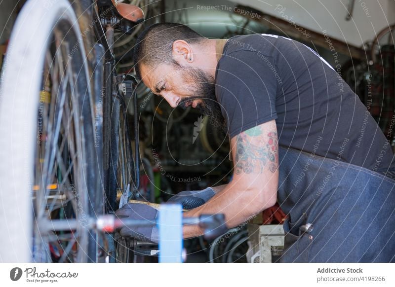 Konzentrierter Mann repariert Fahrrad in Garage Reparatur Fahrzeug Meister vorbereiten Fähigkeit Arbeitsplatz professionell männlich Rad Rand Dienst Reifen