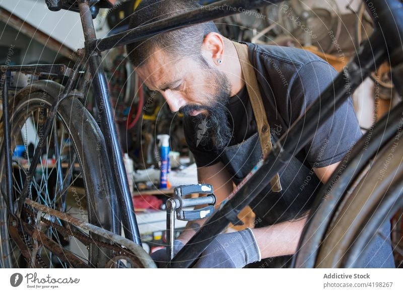 Konzentrierter Mann repariert Fahrrad in Garage Reparatur Fahrzeug Meister vorbereiten Fähigkeit Arbeitsplatz professionell männlich Rad Rand Dienst Reifen