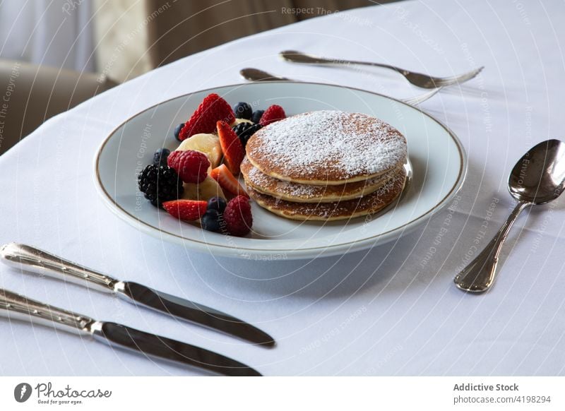 Leckere Pfannkuchen mit Beeren auf dem Tisch im Restaurant serviert Frühstück Zucker Pulver süß lecker Lebensmittel Banane Café Gebäck Feinschmecker Mahlzeit