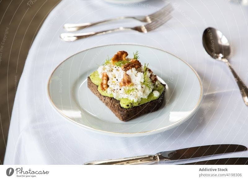 Leckerer Avocado- und Ricotta-Toast auf einem Teller serviert Zuprosten Walnussholz Frühstück Gesundheit lecker Lebensmittel Mahlzeit geschmackvoll Ernährung