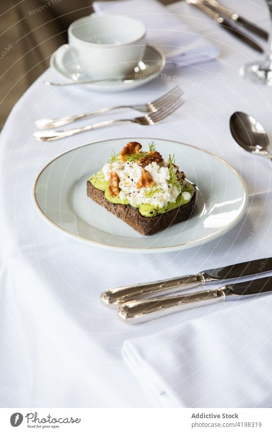 Leckerer Avocado- und Ricotta-Toast auf einem Teller serviert Zuprosten Walnussholz Frühstück Gesundheit lecker Lebensmittel Mahlzeit geschmackvoll Ernährung