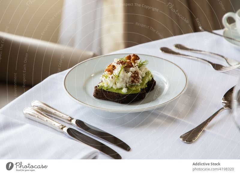 Leckerer Avocado- und Ricotta-Toast auf einem Teller serviert Zuprosten Walnussholz Frühstück Gesundheit lecker Lebensmittel Mahlzeit geschmackvoll Ernährung