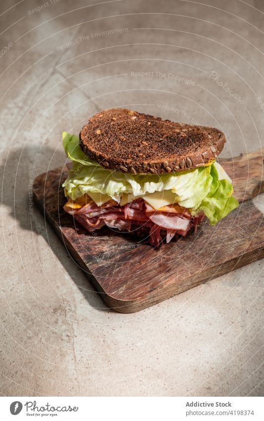 Gesundes Sandwich mit Blattsalat und Speck Belegtes Brot Salat knirschen Zuprosten appetitlich Holzplatte hölzern Ernährung Restaurant lecker kulinarisch