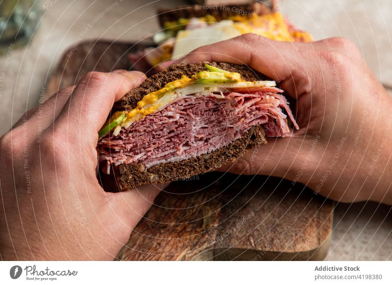 Crop-Person beim Mittagessen mit Sandwich und einem Glas Wasser Klient Belegtes Brot Zuprosten Salat Speck Restaurant geschmackvoll Kalk frisch Café Schinken