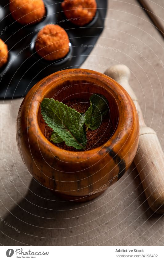 Mörser mit gemahlenem rotem Pfeffer und Minzblatt mit Stößel Minenwerfer Stössel Pulver Paprika Minze Blatt gemahlener Pfeffer Gewürz Werkzeug Käsekugel