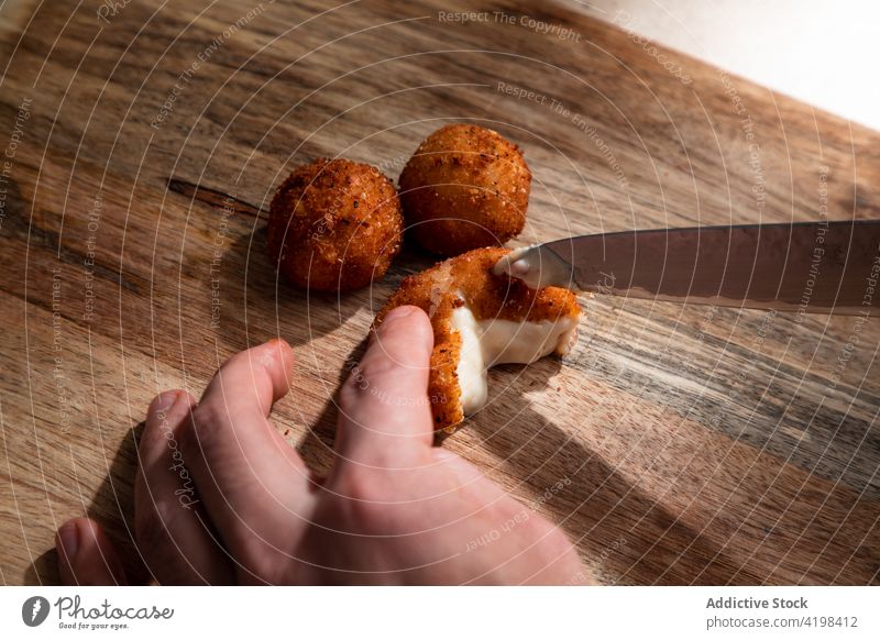 Koch schneidet knusprig gebratene Käsebällchen Küchenchef Knusprig frittiert Käsekugel geschnitten geschmackvoll knirschen Messer Mahlzeit appetitlich Tisch