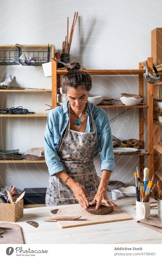 Frau stellt in einer Werkstatt Tonwaren her kreieren Lächeln positiv Skulptur Töpferwaren Fähigkeit Klasse Talent Glück Erwachsener lässig Schürze kreativ