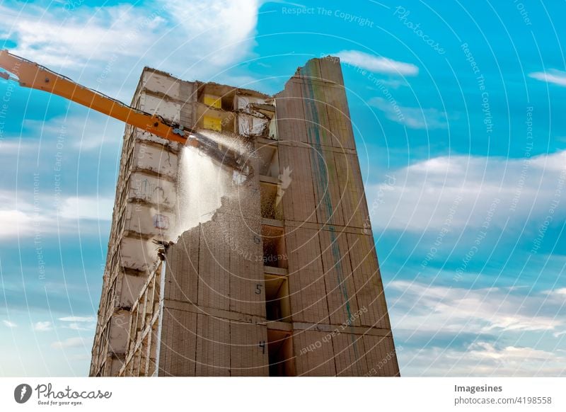 Abrisshaus. Kran wirft Wasser. Hochhausgebäude auf der Baustelle gegen blauen Wolkenhimmel. Abriss eines Hochhauses in der Innenstadt Gebäude Wohnung