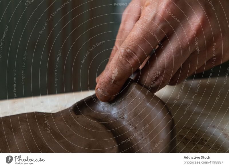 Gesichtsloser Mann bei der Herstellung von Tonprodukten in einer Werkstatt rollen Töpferwaren Arbeit Kunstgewerbler Tonwaren handgefertigt Handwerk Fähigkeit