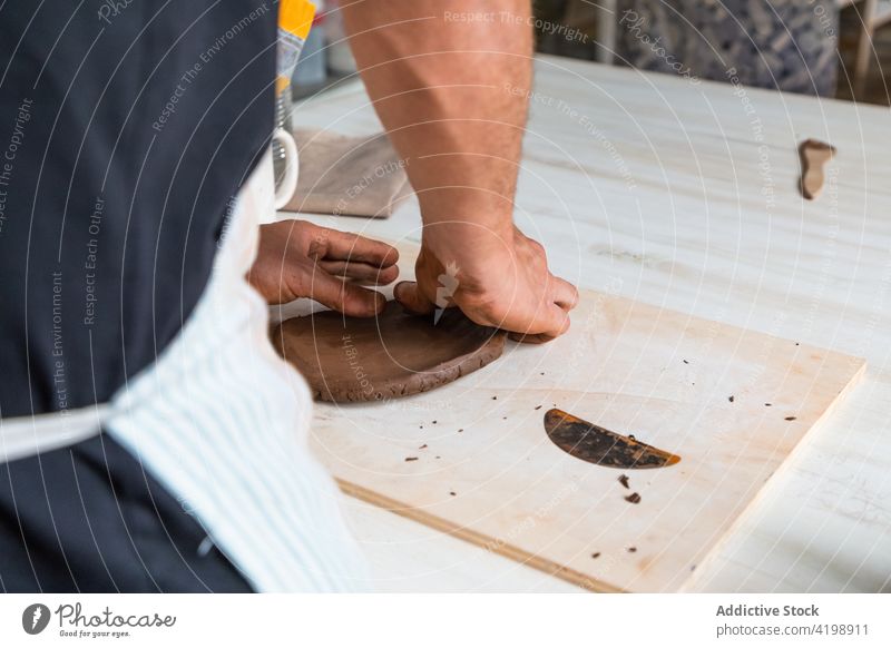 Gesichtsloser Mann bei der Herstellung von Tonprodukten in einer Werkstatt rollen Töpferwaren Arbeit Kunstgewerbler Tonwaren handgefertigt Handwerk Fähigkeit