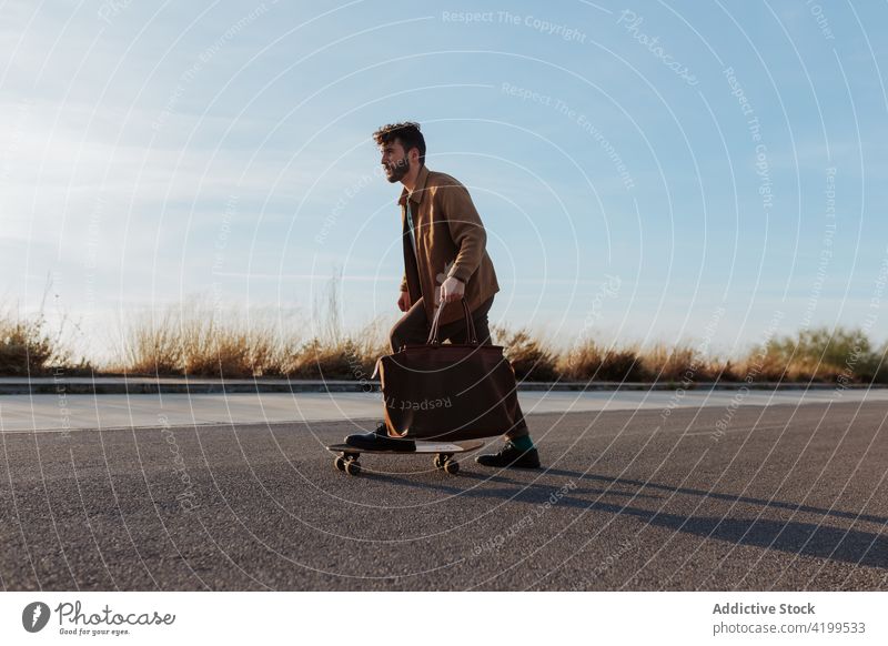 Junger bärtiger Skater mit Tasche fährt auf der Straße Mann Longboard Fähigkeit Mode Stil Skateboard Asphalt Mitfahrgelegenheit Hobby Aktivität männlich