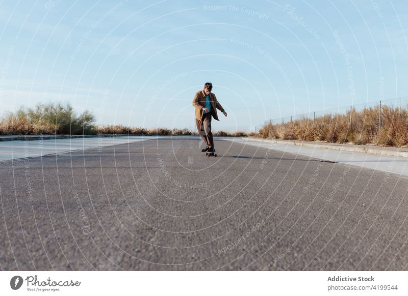 Junger bärtiger Skater auf Asphaltstraße Mann Mitfahrgelegenheit Straße Skateboard Landschaft ländlich Natur Hobby Subkultur üben Fähigkeit männlich Energie