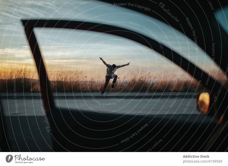 Skater, der einen Trick auf dem Skateboard auf einer asphaltierten Straße im Sonnenuntergang vorführt Mann ausführen Kickflip Natur Freiheit springen Asphalt