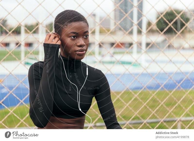 Kurzhaarige schwarze Frau, die mit einem Mobiltelefon und Kopfhörern Musik hört Afroamerikaner Smartphone Headset Gesang zuhören Kurze Haare Porträt benutzend