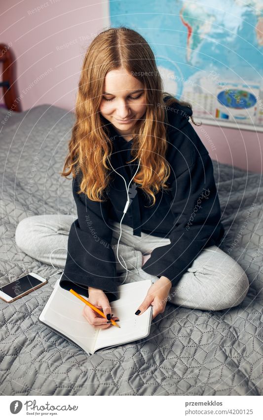 Schüler beim Lernen zu Hause. Junge Frau macht sich Notizen, liest und lernt vom Notizblock Bildung im Innenbereich arbeiten Person Hinweis Notebook studierend