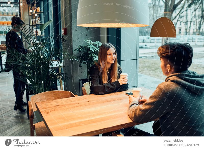 Freunde, die sich unterhalten, miteinander reden, Kaffee trinken, in einem Café sitzen. Junger Mann und Frau, die sich im Café entspannen, eine Pause machen