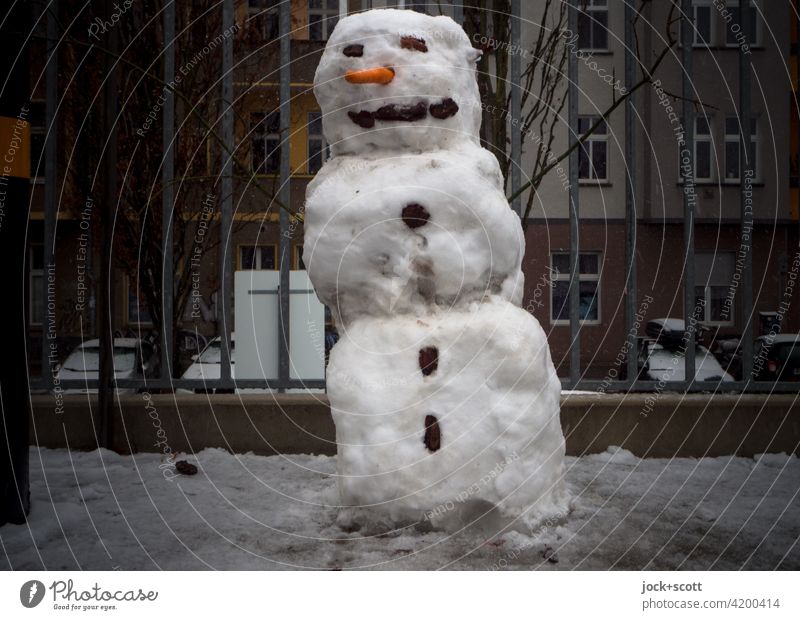 schiefer kleiner Schneemann wiegt sich anmutig im Rhythmus Winter kalt Kreativität Prenzlauer Berg Berlin Fassade Metallzaun Winterstimmung Umwelt diesig