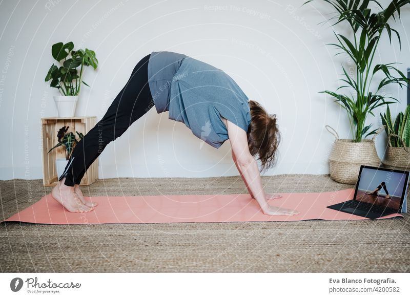 Nahaufnahme von reifen kaukasischen Senior Frau übt Yoga-Pose zu Hause. mit Laptop für Online-Klasse mit Lehrer. Gesunde und Technologie Lebensstil Seniorin