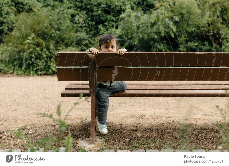 Kind spielt auf Gartenbank 1-3 Jahre Kaukasier Bank Lifestyle Außenaufnahme Mensch Farbfoto Kleinkind Kindheit mehrfarbig Freizeit & Hobby niedlich Park Glück