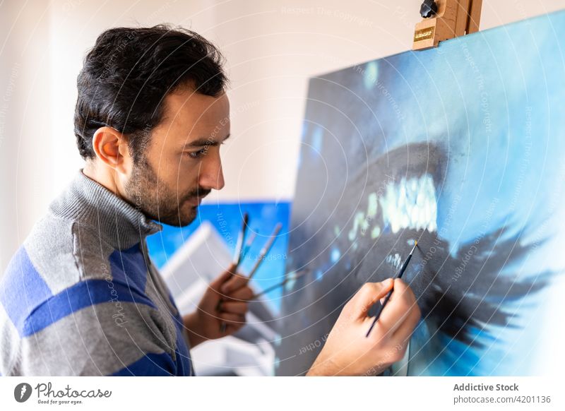 Hispanischer männlicher Künstler malt ein Bild in einem Workshop Farbe Leinwand Kunstwerk kreativ Design Talent professionell Mann Werkstatt Bürste Anstreicher