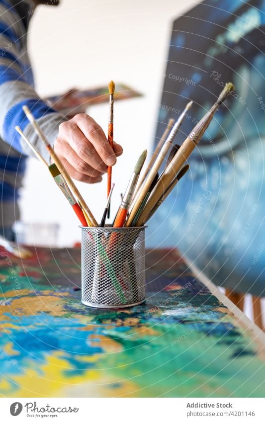 Crop Artist mit Pinseln und Kunstbild im Atelier Anstreicher nehmen Pinselblume Malerei Kunstwerk Werkzeug Vorrat professionell Mann Werkstatt Künstler Leinwand