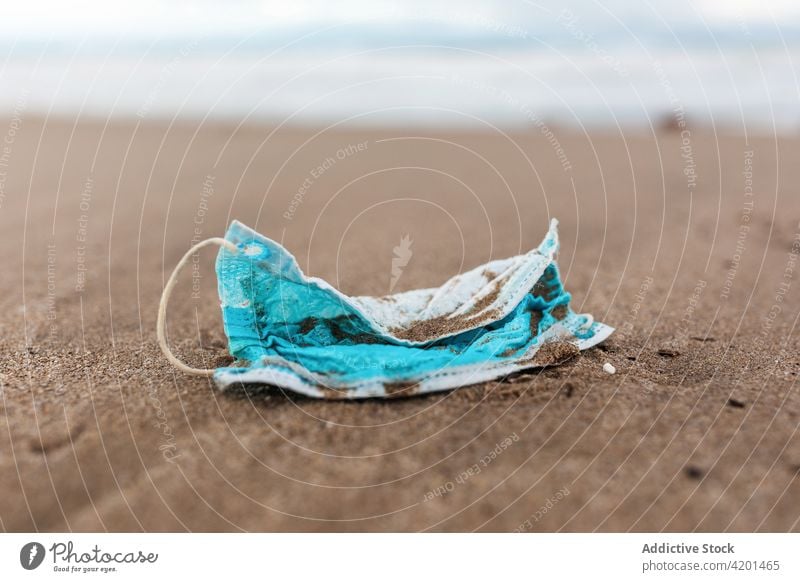 Schmutzige medizinische Maske am sandigen Meeresstrand Mundschutz verschmutzen MEER Strand Abfall Umwelt Konzept Kunststoff Müll Wasser verwendet dreckig